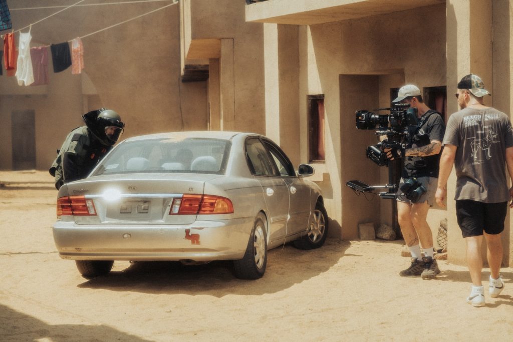 woman in white shirt standing beside gray sedan